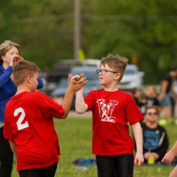 Two young boys in Whitmore Lake tee shirts giving each other a high five.