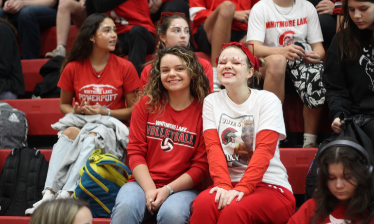 A young boy and a young girl are on the playground and they are smiling at the camera.