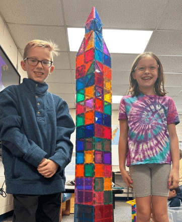 Two young boys looking at the camera while standing on a bridge on a playground.
