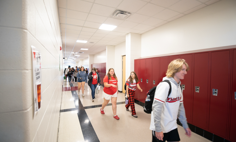 A young boy and a young girl are on the playground and they are smiling at the camera.